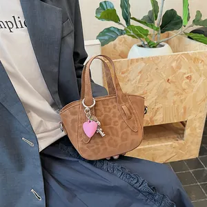 Dettaglio della borsa leopardata con ciondoli a cuore rosa e chiave argentata sui manici