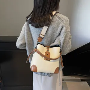 Vue détaillée du sac seau crème avec bordure marron et bandoulière large en tissu
