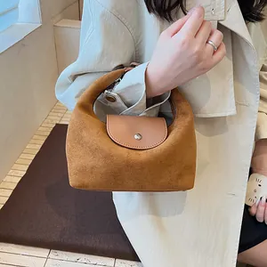 Detail of caramel suede hobo bag with silver metallic snap button and leather flap