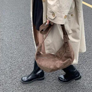 Detail of dark brown suede shoulder bag with knot decoration and visible stitching