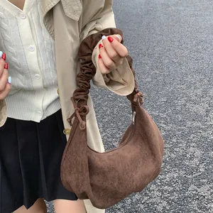 Detail of a brown suede hobo bag featuring elegant ruched cloud-style handles and drawstrings