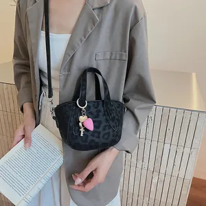 Dettaglio della mini borsa leopardata con ciondoli a cuore rosa e tracolla rimovibile