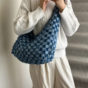 Detail of checkered denim hobo bag featuring frayed edges and vintage blue texture