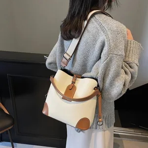 Détail du sac seau en cuir beige avec finitions marrons porté par un mannequin de mode