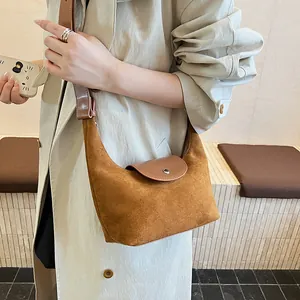 Detail view of caramel suede shoulder bag styled with a beige trench coat on a model
