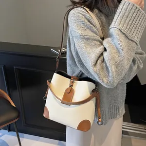 Détail d'un sac seau blanc vintage avec garniture en cuir marron porté par un mannequin