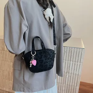 Dettaglio di una borsa leopardata vintage con ciondoli a cuore rosa e chiave