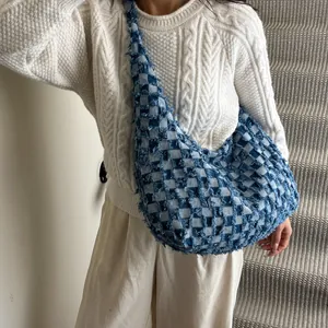 Detail of vintage denim checkered crossbody bag with frayed edges worn by a model