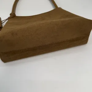 Close-up of matte suede shoulder bag featuring precise tonal stitching and fine texture