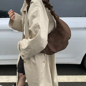 Detailed view of dark brown suede crescent bag with elegant pleated shoulder strap design