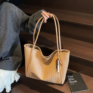 Close-up of brown woven leather tote bag featuring a colorful beaded tassel charm
