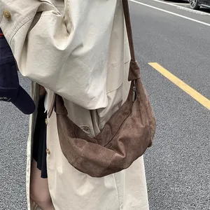 Detail of dark brown suede hobo bag with zipper on a beige trench coat background