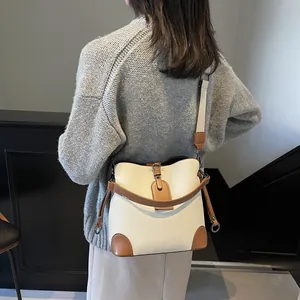 Détail du sac seau blanc crème avec garniture en cuir marron et large bandoulière