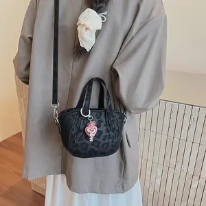 Dettaglio di una mini borsa leopardata nera con un ciondolo a cuore rosa acceso