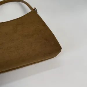 Detail view of brown faux suede shoulder bag featuring fine texture and silver metal hardware