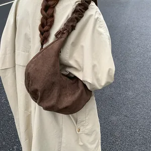 Detail of coffee brown pleated crescent bag showing suede texture and gathered strap design