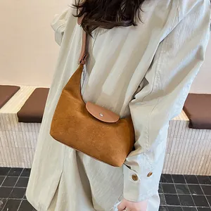 Close-up of brown suede and leather hobo bag on model in a stylish beige trench coat