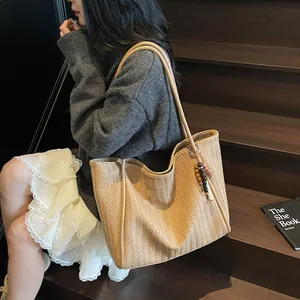 Detail of khaki woven tote bag with V-shaped pattern and beaded charm decoration