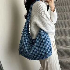 Close-up of blue checkered denim hobo bag with frayed edges and oversized casual design