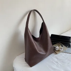 Close-up of brown pebbled leather tote bag shown with office desk accessories