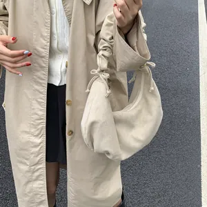 Close-up of beige drawstring hobo bag featuring scrunchie handle and bow details