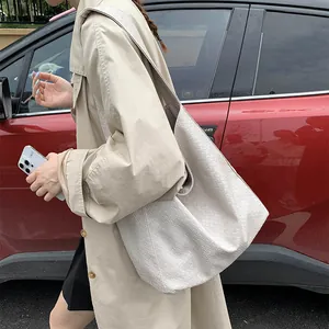 Detail of a large woven hobo bag in cream leather shown in a lifestyle street setting