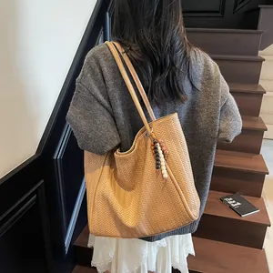 Detail of light brown tote bag featuring V-shaped woven texture and beaded tassel