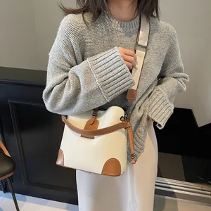 Détail du sac seau crème avec bordure en cuir marron et large bandoulière en tissu