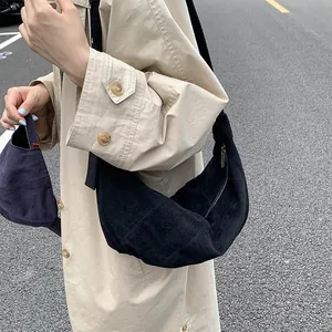 Detail of minimalist black matte suede hobo bag worn with a casual khaki trench coat