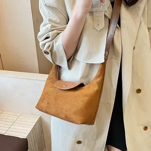 Detail view of brown suede crossbody bag with leather strap and silver snap closure