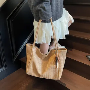 Detailed view of large khaki tote bag with woven texture and beaded pendant decoration