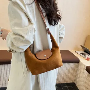 Detail view of ginger brown suede hobo bag with smooth leather trim and metal buckle