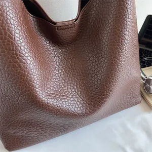 Close-up of dark brown tote bag with litchi grain texture and professional office items