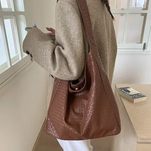 Detail of caramel brown woven tote bag showing premium PU leather texture and shoulder strap