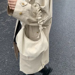Detail of soft cream pleated shoulder strap on a minimalist suede dumpling bag