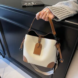 Détail du sac seau texturé litchi avec bordure marron et large bandoulière beige