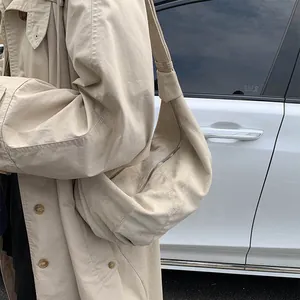 Beige matte suede crescent bag worn by model with matching trench coat in outdoor setting