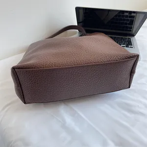 Macro shot of brown leather tote bag showing durable stitching and bottom structure