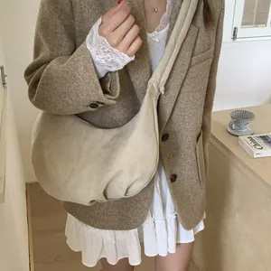 Detail of a large beige canvas hobo bag with drawstring pleats and wide shoulder strap