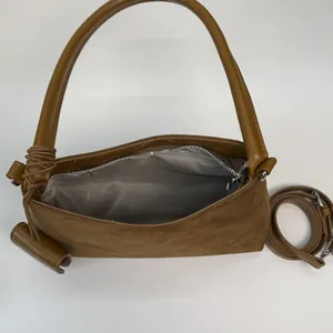 Detail view of deep brown suede handbag interior with zipper pocket and shoulder strap