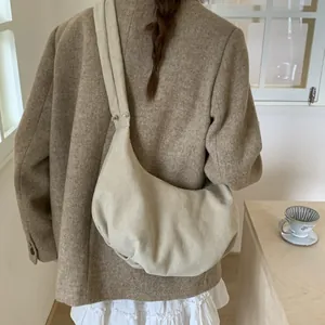 Minimalist cream shoulder bag shown on model featuring soft fabric and slouchy design