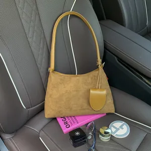Detail of brown suede underarm bag with mini pouch on a leather car seat