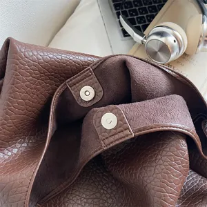 Detail of dark brown tote bag showing dual magnetic closure and textured lychee pattern
