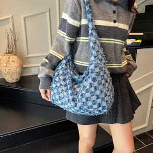 Detail of frayed edge denim stitching on the blue and white checkered hobo shoulder bag