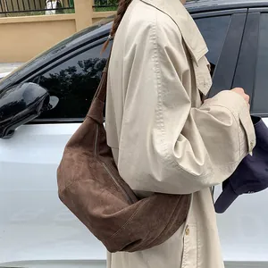 Close-up of deep brown suede hobo bag worn with a beige trench coat in street style