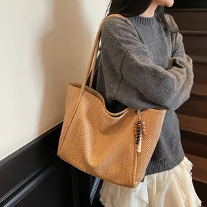 Detail of light brown tote bag featuring fine V-weave texture and colorful bead charm