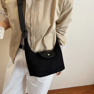 Detail view of black nubuck crossbody bag with leather flap and wide adjustable strap