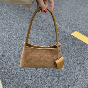 Detail of dark brown suede baguette bag with matching coin pouch in street style
