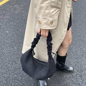 Detail of ruched handle and matte suede texture on black hobo bag styled with trench coat