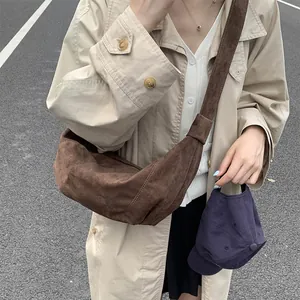 Detail of a brown matte suede crescent crossbody bag with comfortable wide shoulder strap
